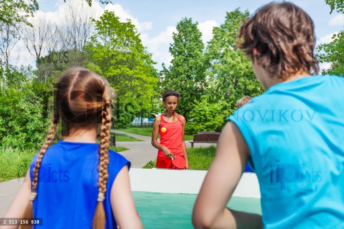 Four teenage friends playing ping pong outside