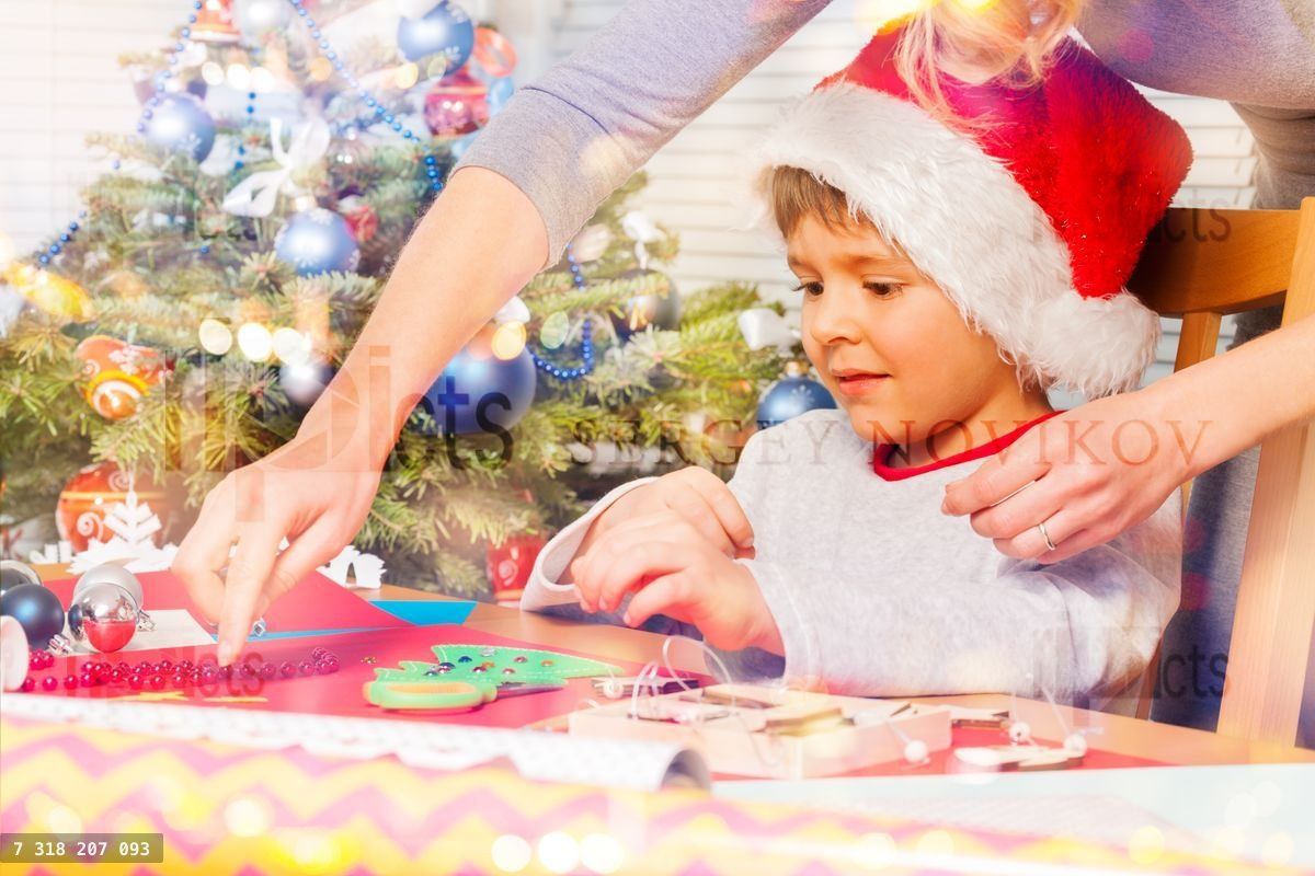 Woman helping her son to decorate holiday ornament