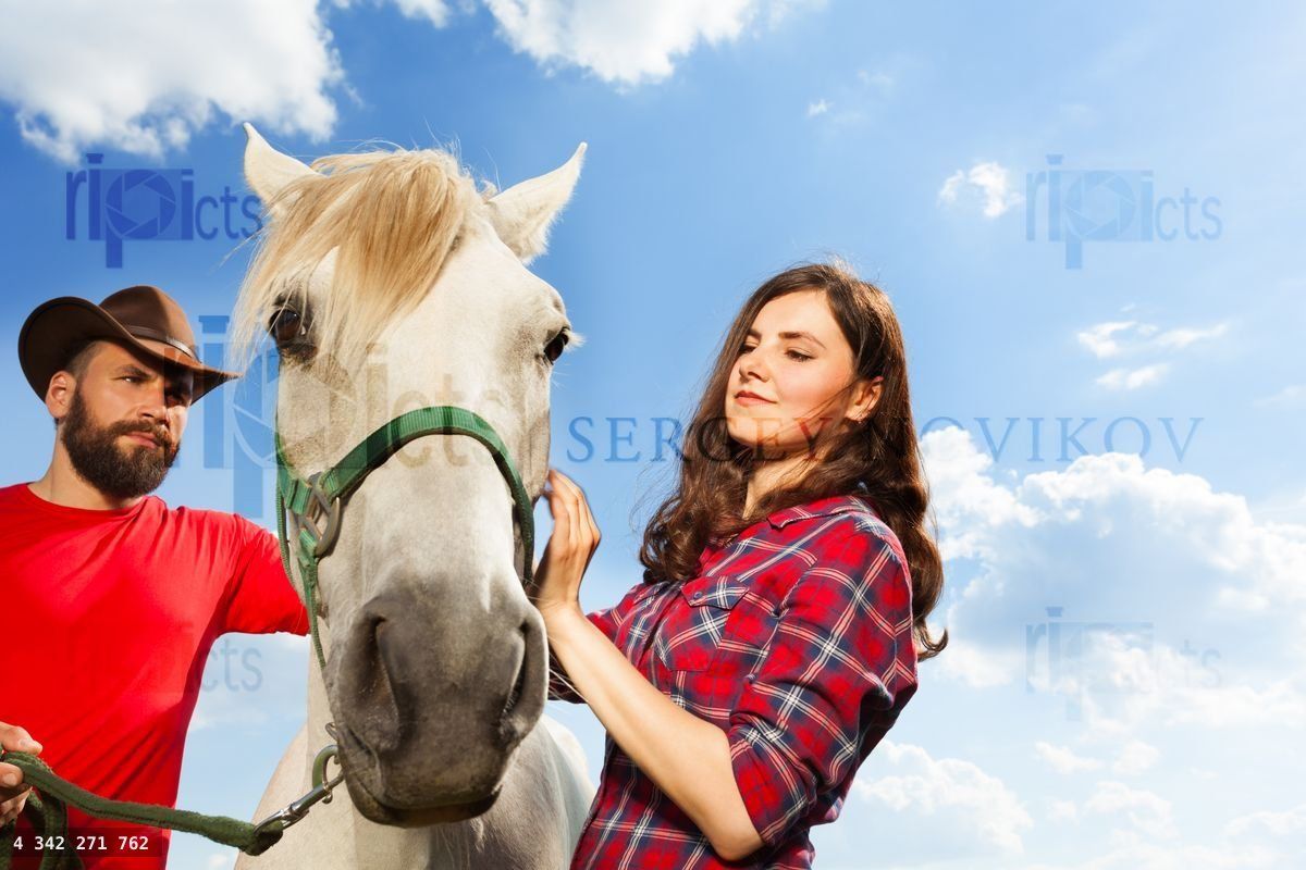 Young couple with their horse against the blue sky