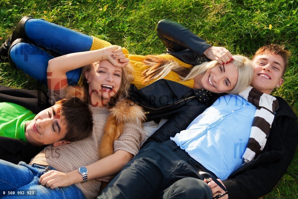 Group of four young people laying in the grass