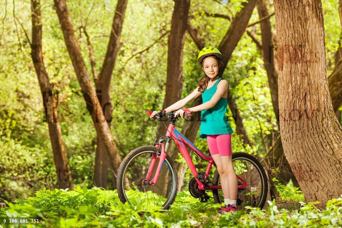 Young girl with her mountain bike in sunny forest