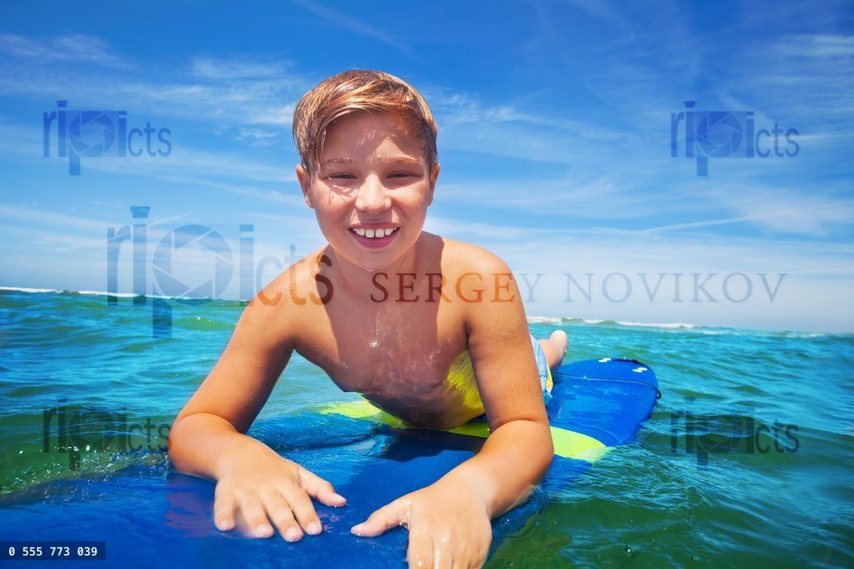 Close portrait of happy surfing boy on surfboard