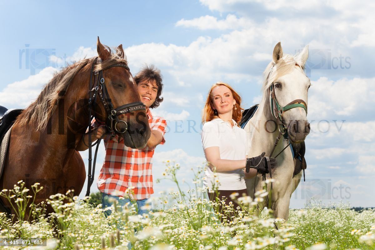 Young happy couple with their purebred horses
