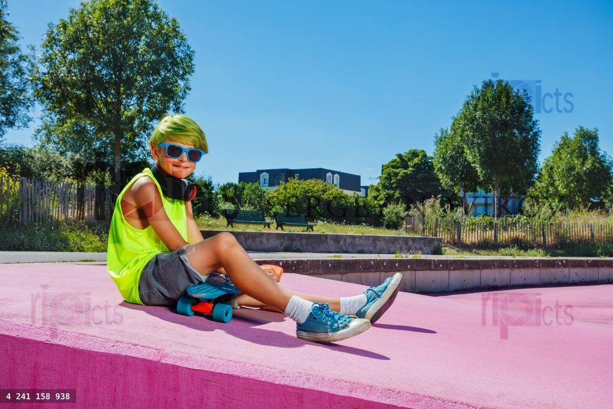 Handsome young preteen boy with green hair sit on ramp