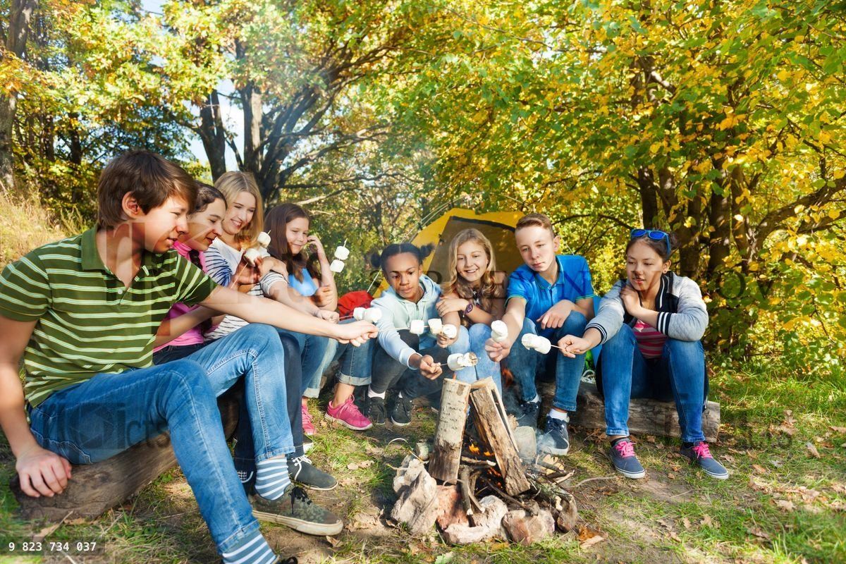 Friends on campsite grill marshmallow near tent