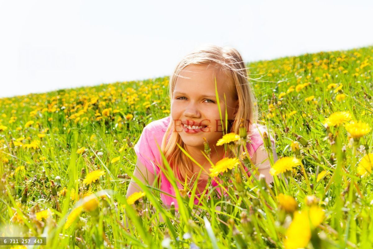 Happy blond girl in the meadow with flowers