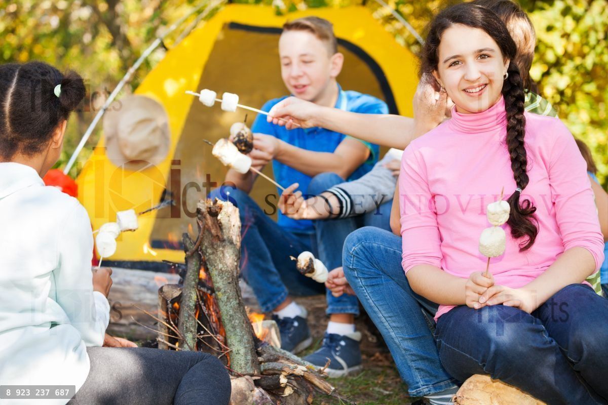Friends with marshmallow on campsite near bonfire