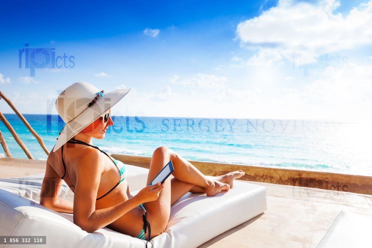 Young woman with hat laying and reading e book
