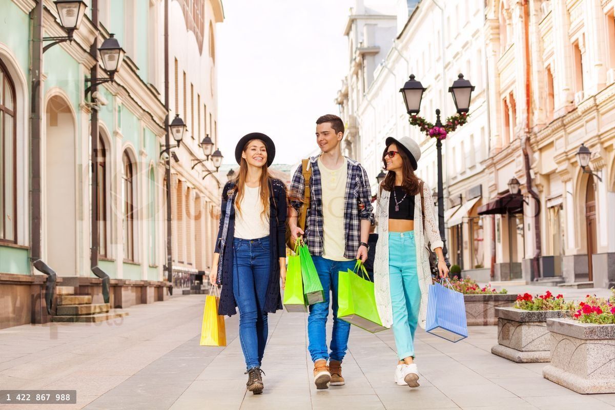Three happy friends walking with shopping bags