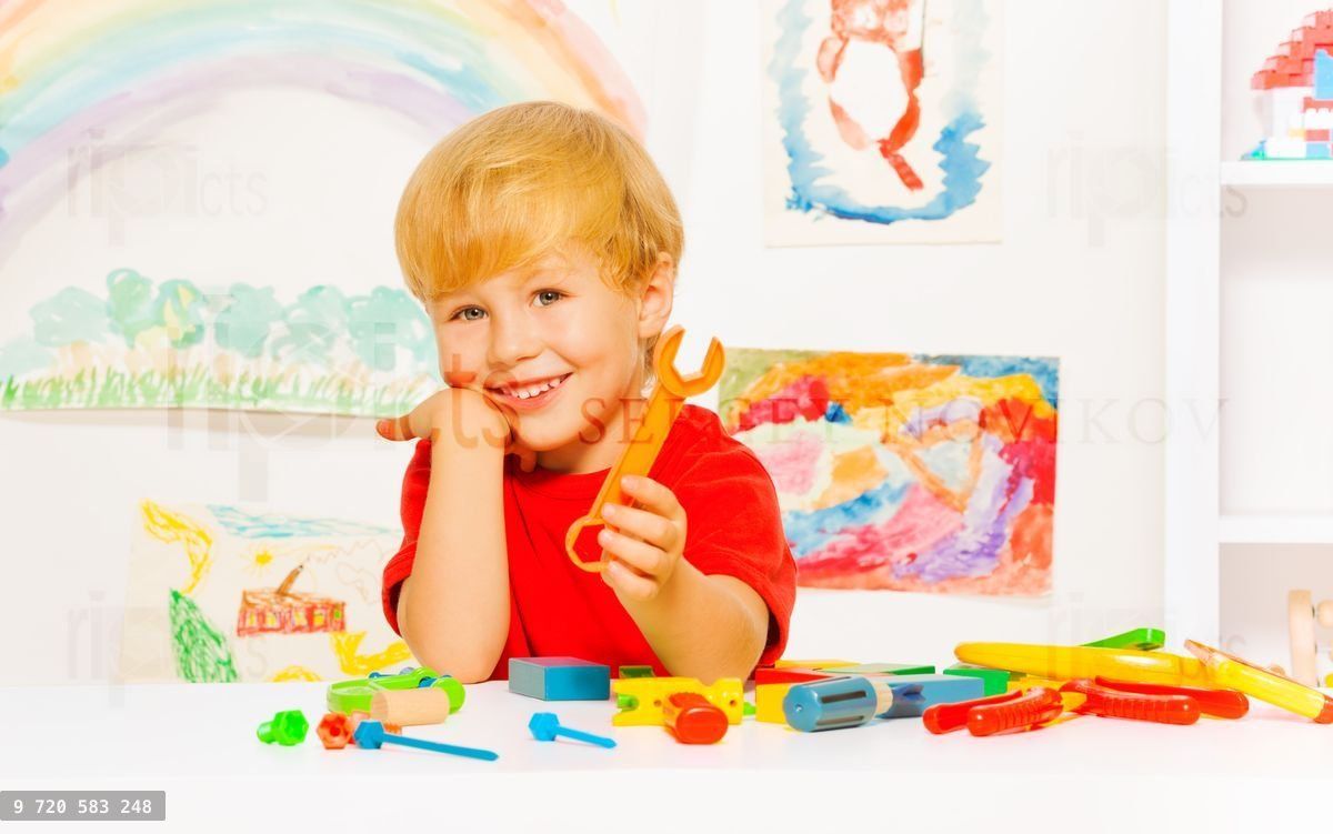 Handsome blond boy with wrench in kindergaten