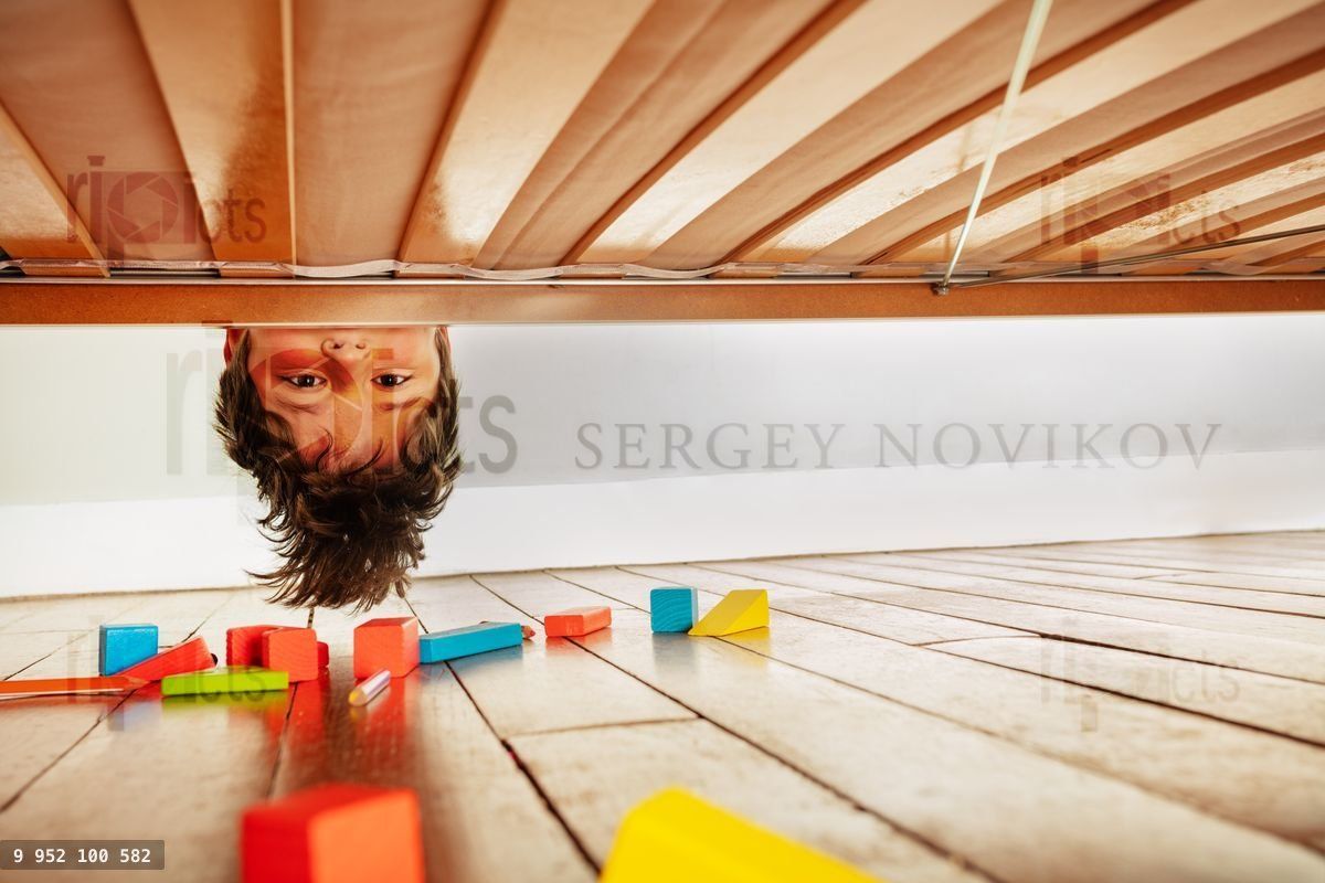 Funny portrait of a boy look down under the bed