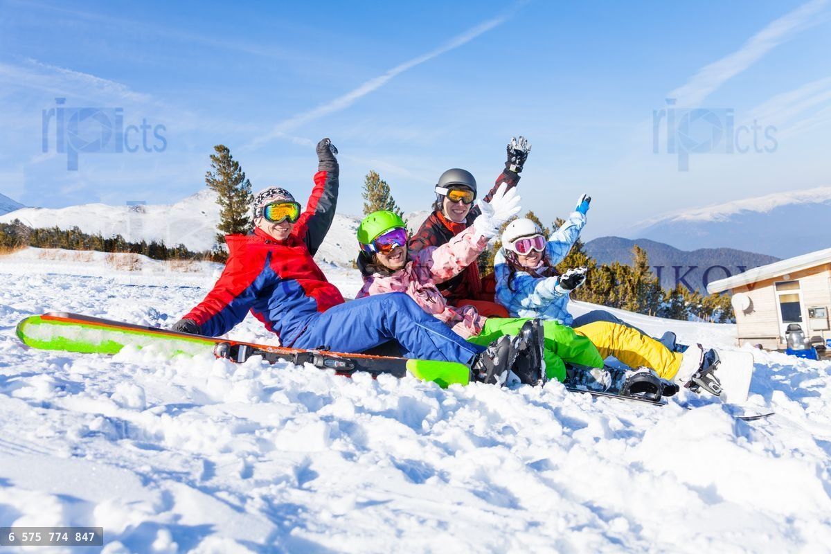 Four happy friends wearing goggles with hands high