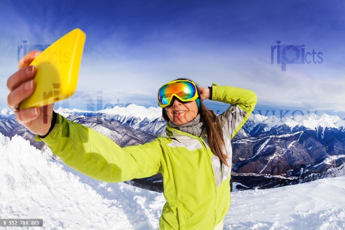 Woman take selfie over mountain and ski tracks