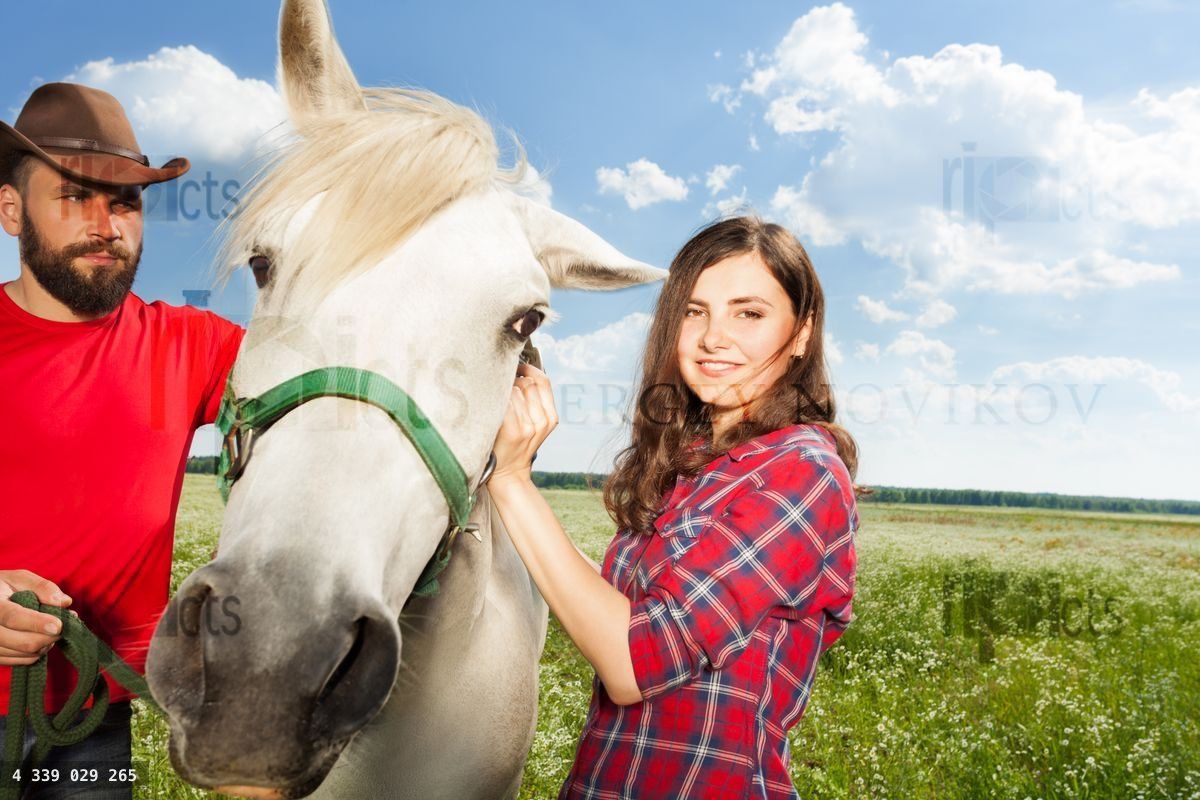 Young couple with their white horse on rural farm