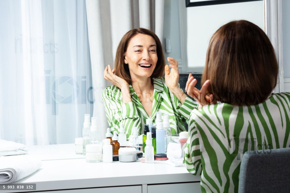 Woman in long sleeved garment pose before makeup mirror