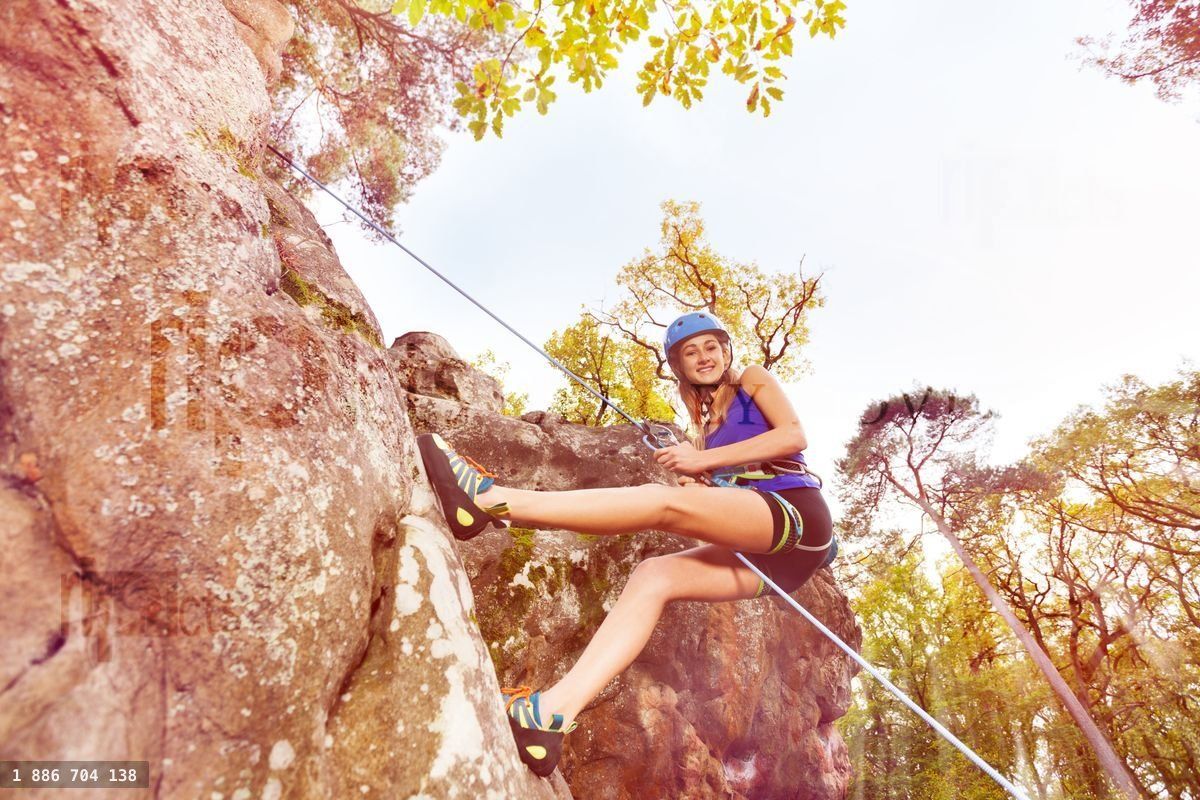 Young woman abseiling training on steep rock