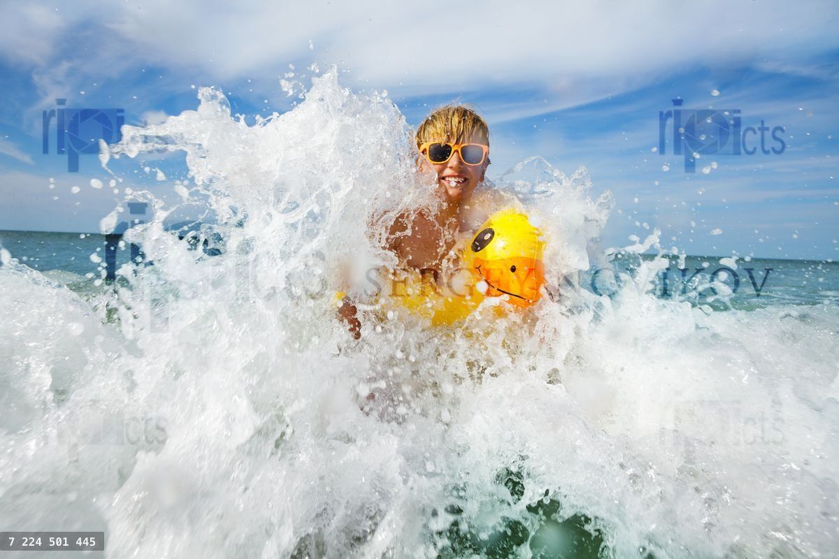 Fun in the sea boy with sunglasses and yellow inflatable duck