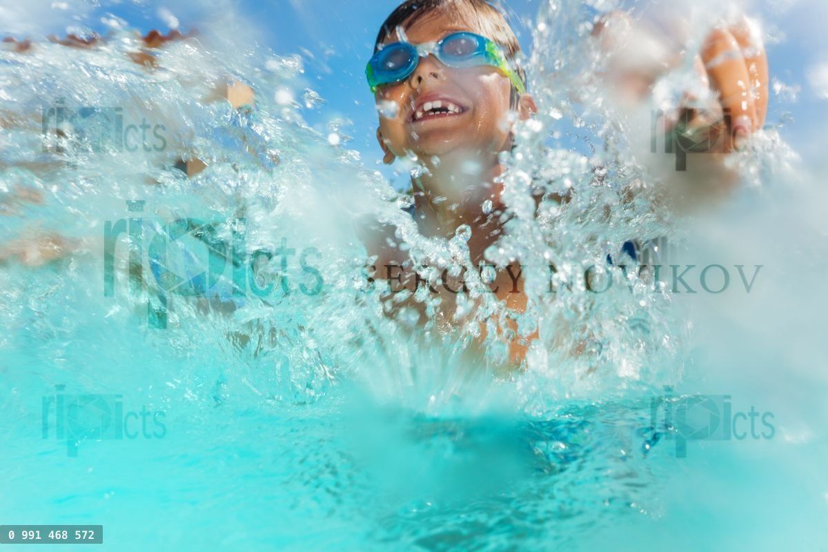 Happy boy having fun splashing water in the pool