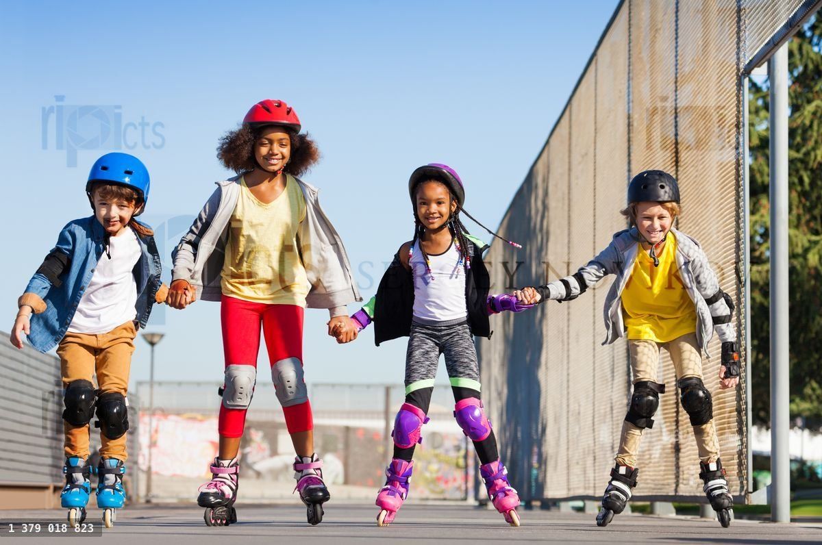 Four smiling friends rollerblading outdoors