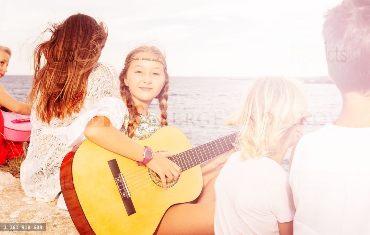 Young girl playing music on acoustic guitar
