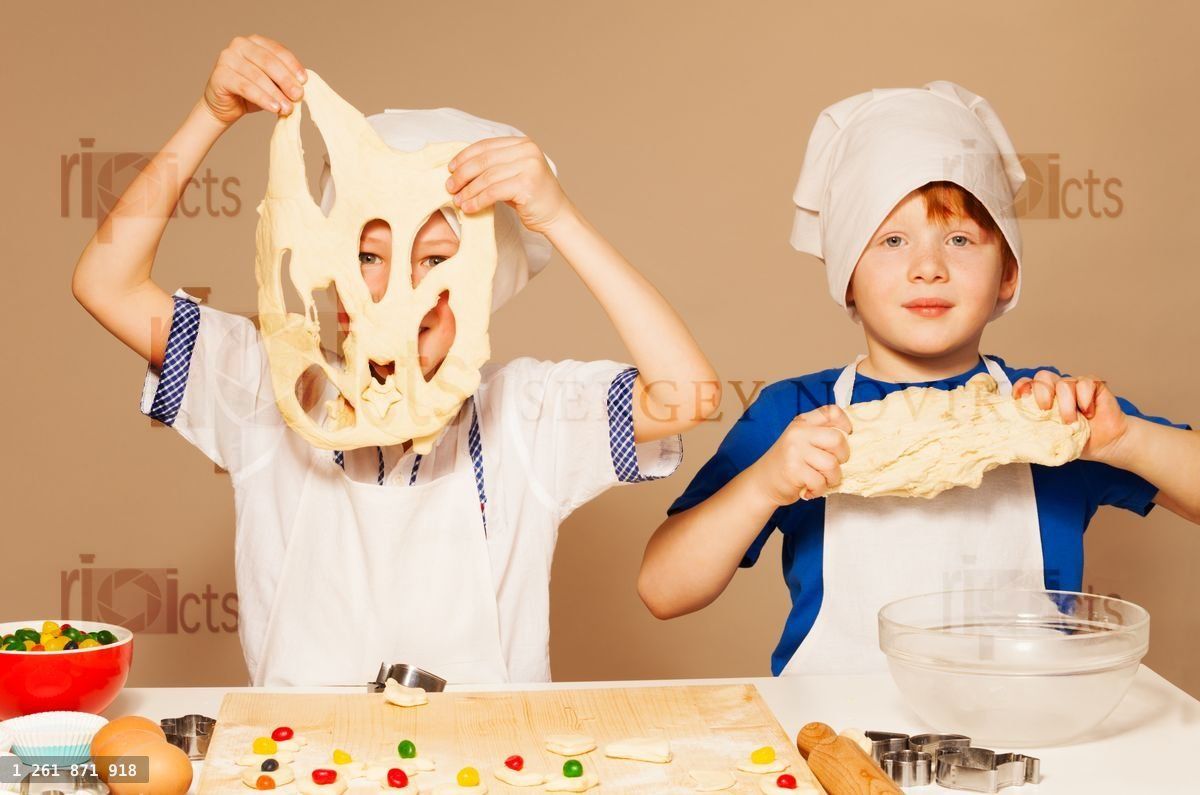 Young bakers having fun kneading dough for cookies