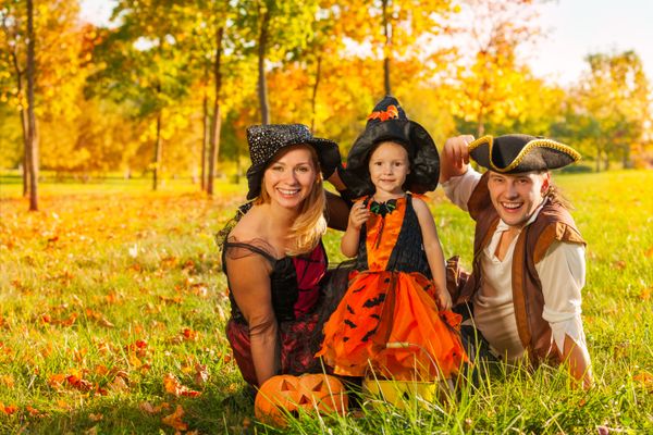 Family in Halloween costumes sitting on the grass