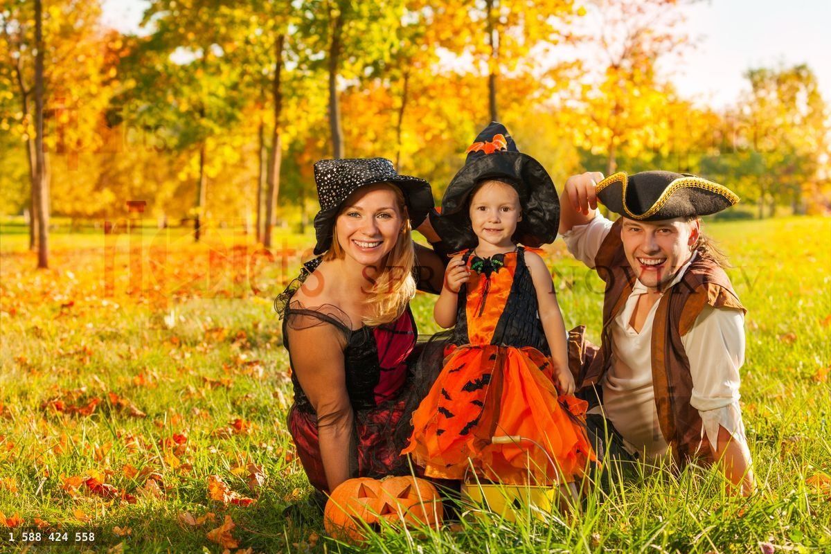 Family in Halloween costumes sitting on the grass