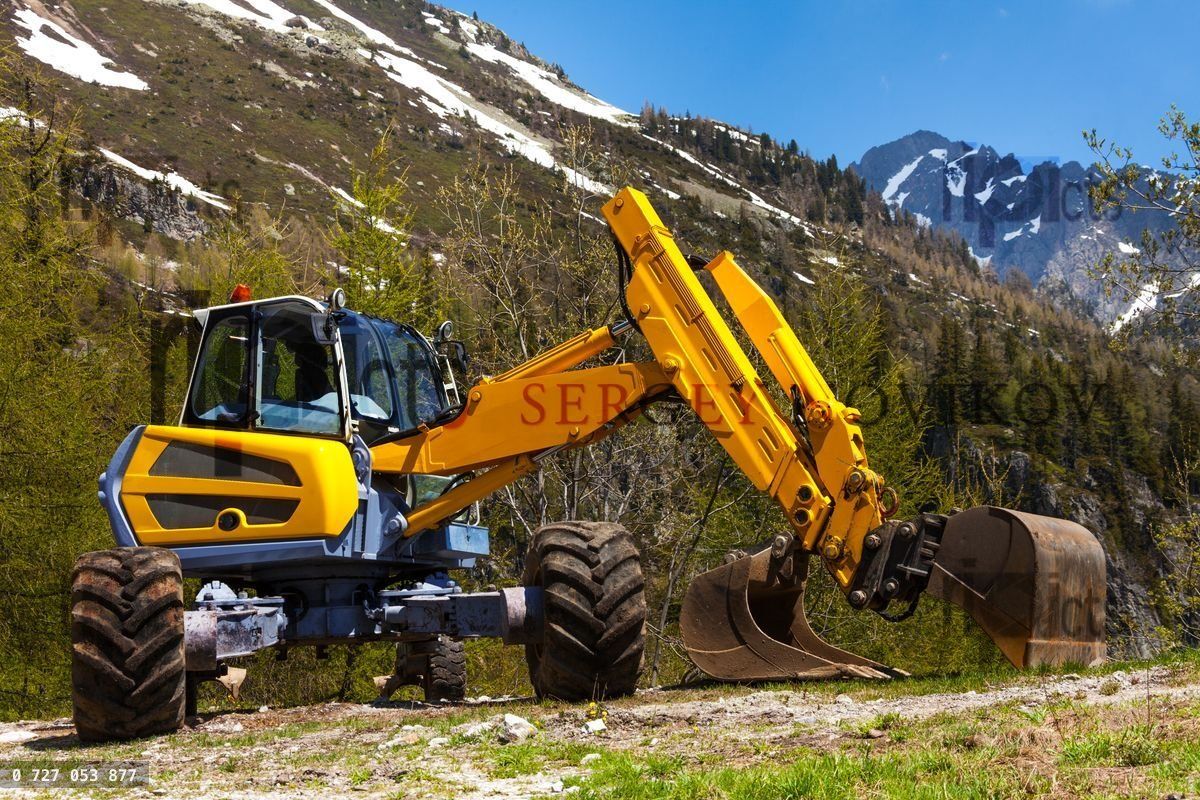 Yellow excavator working near mountains