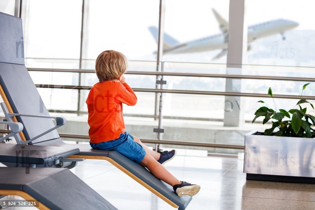 Young boy eagerly watches planes from airport chair