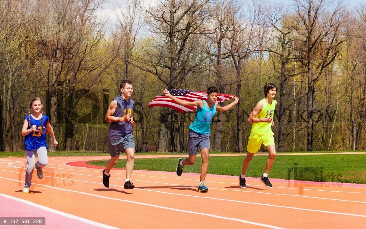 Four young sprinters waving American flag on track