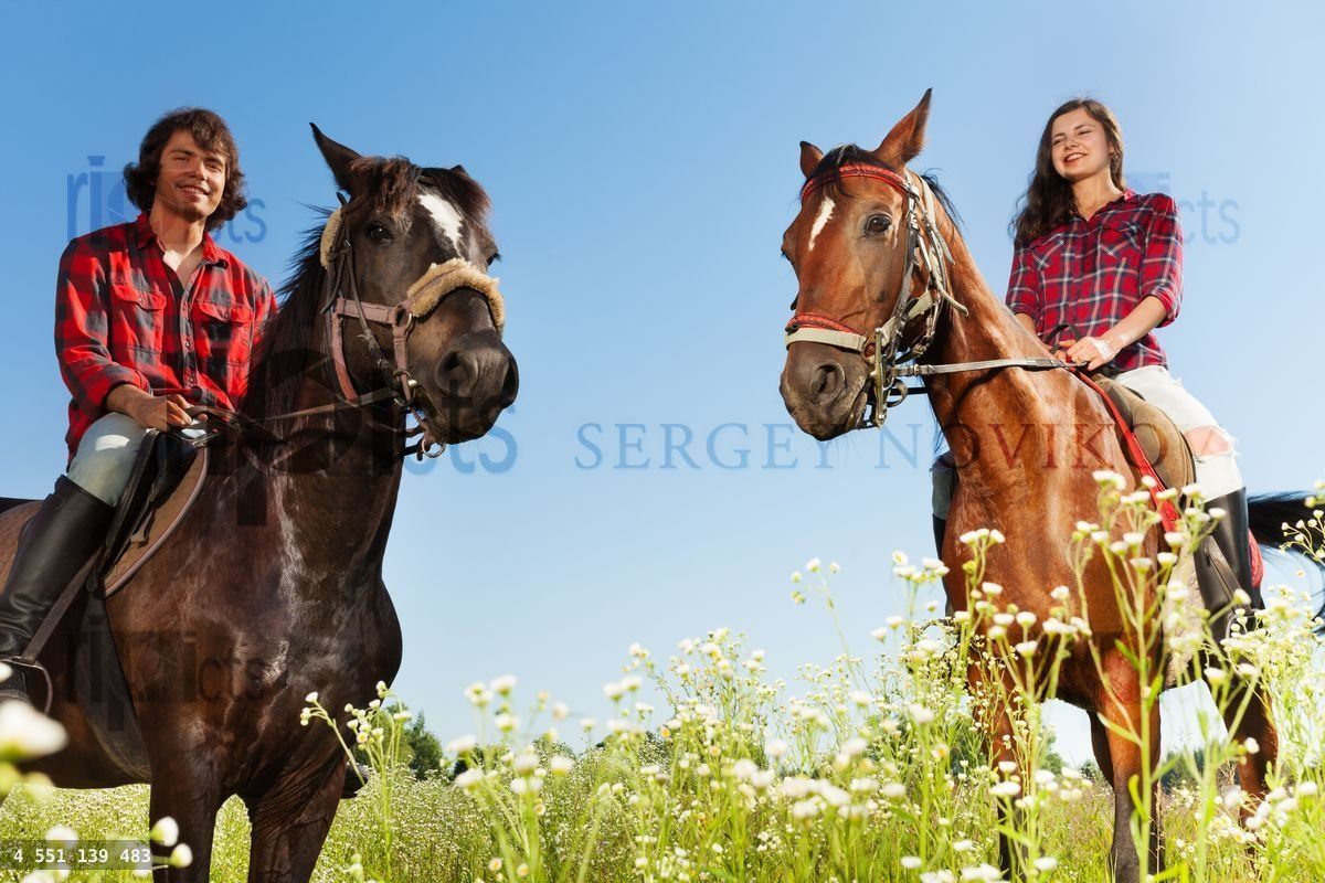 Young people horseback riding in flowery meadows