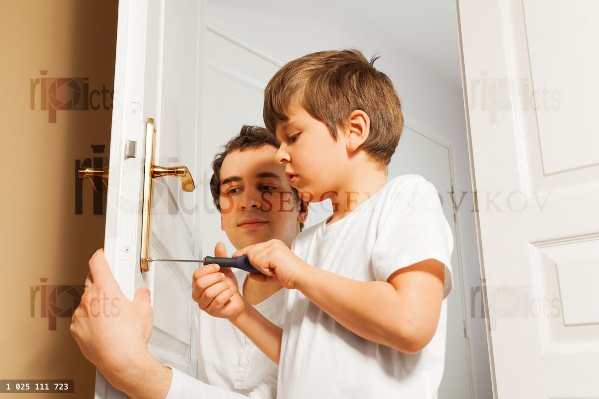 Young father helping his son to fix door handle