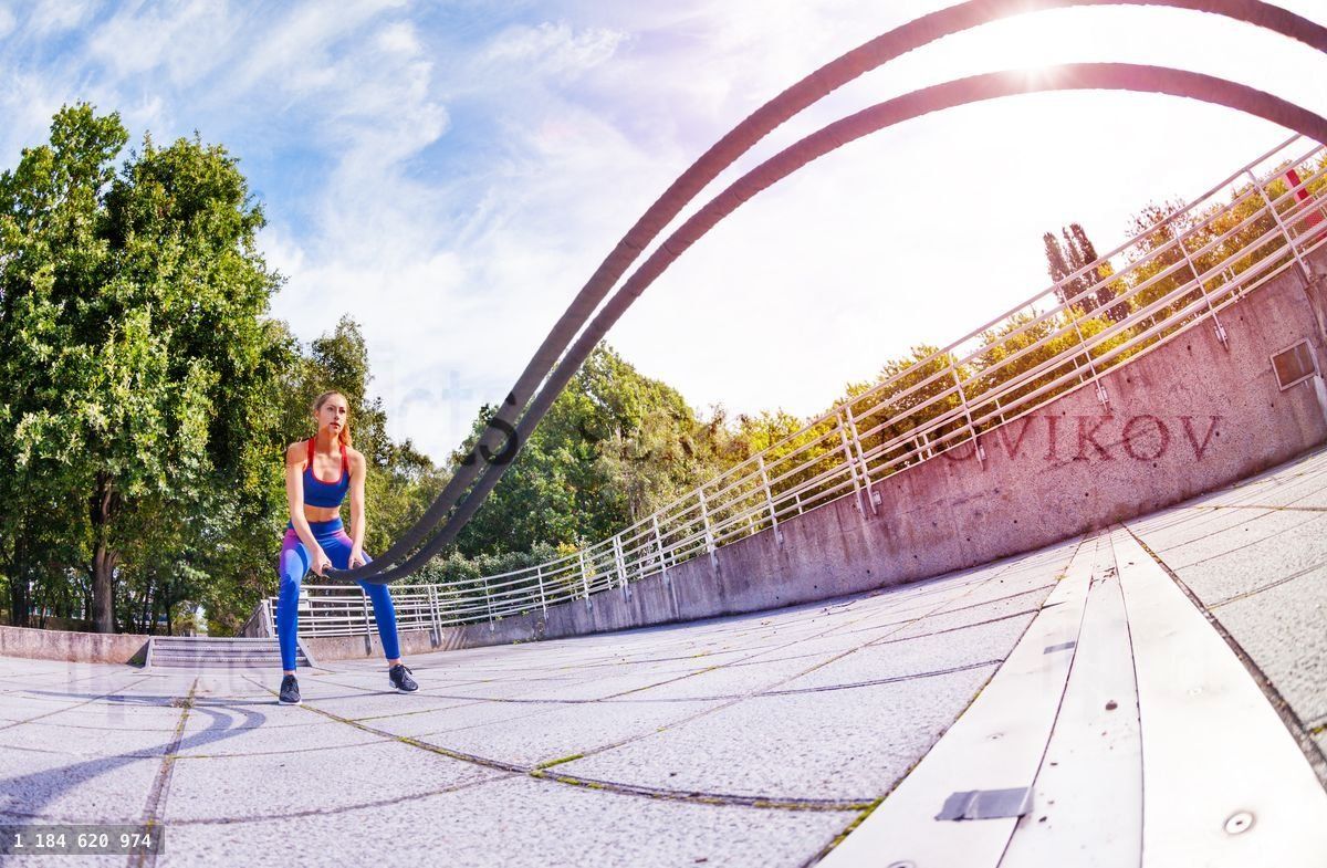 Young woman making wave movement with muscle rope
