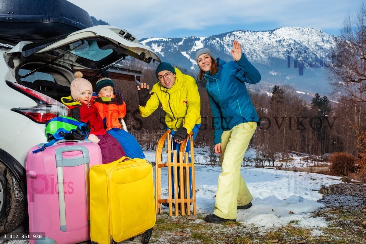 Family mom, dad, children unload baggage at winter destination