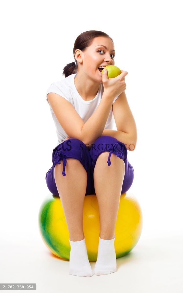 Young woman sit on ball with apple