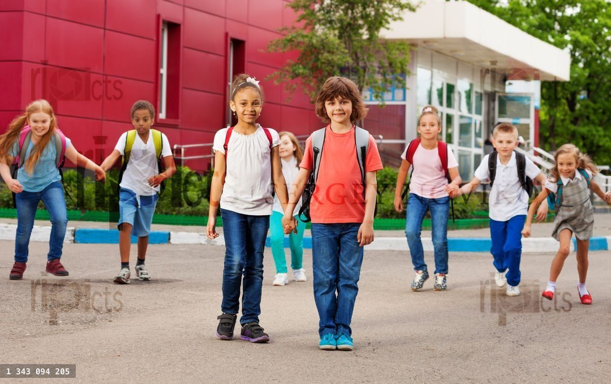 Rows of kids with rucksacks near school walking
