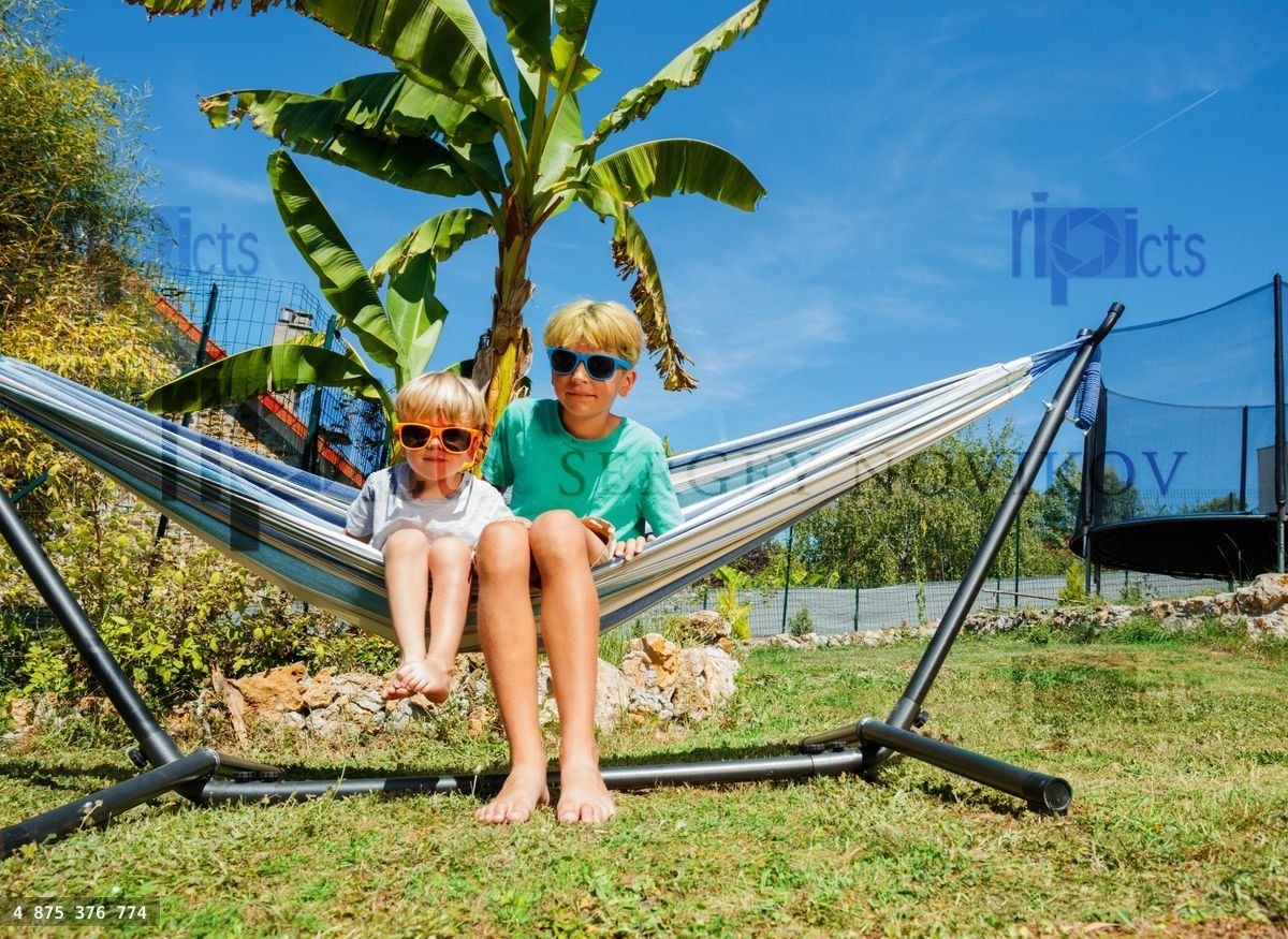 Brothers boys sit in the hammock at backyard garden