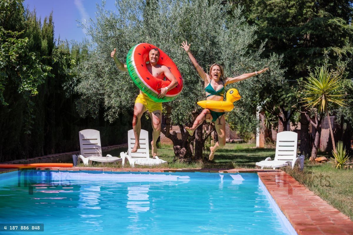 Fun water splash of excited adult couple at summer pool party