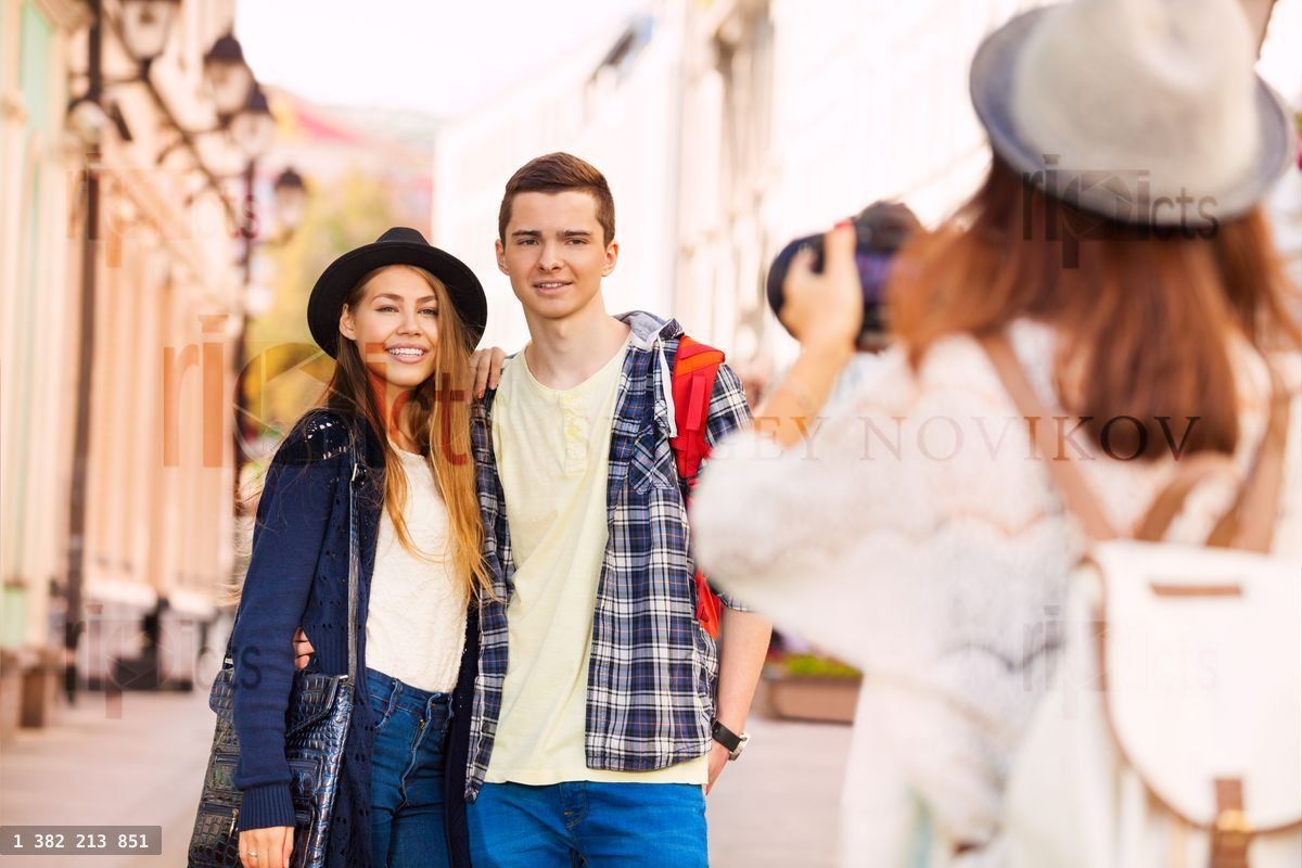 Boy and girl smiling with friend shooting them