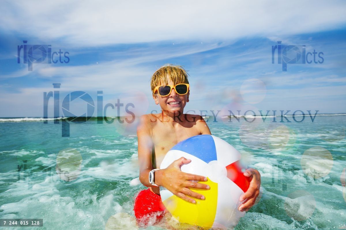 Fun in the sea boy with sunglasses and yellow inflatable ball