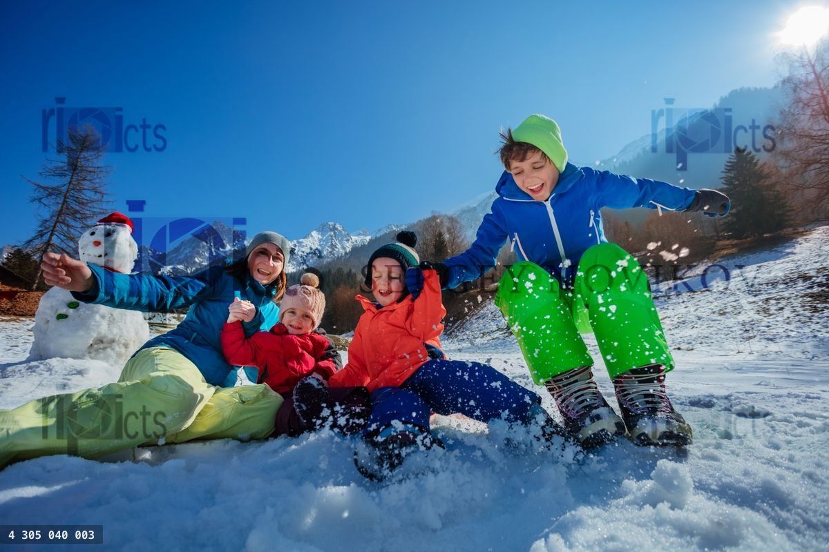 Famille saute dans la neige, éclaboussures enneigées sur des montagnes ensoleillées