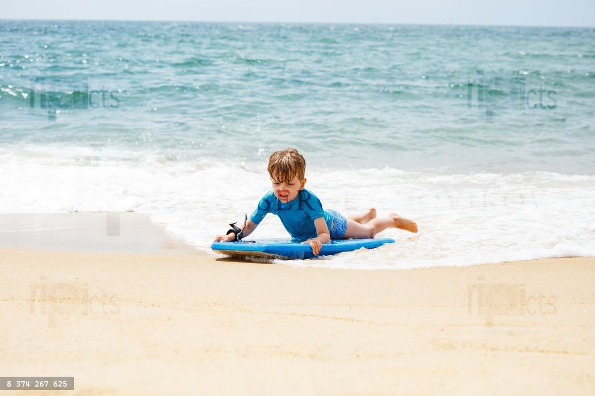 Young boy on a beach enjoying bodyboarding in the ocean waves