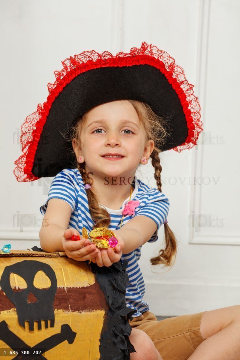 Girl dressed as pirate holds treasures by a decorated box