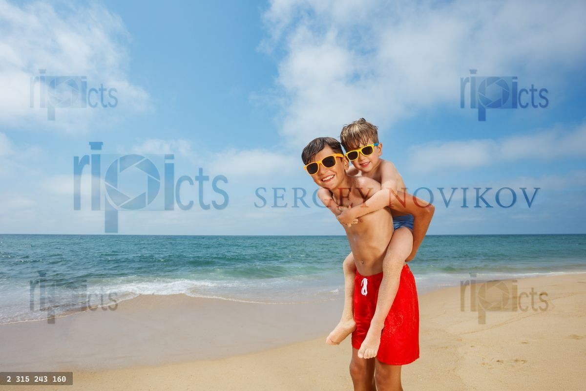 Young brothers in sunglasses share playful moment by seaside