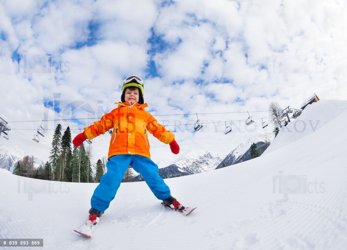 Boy with mask and helmet skiing on ski resort