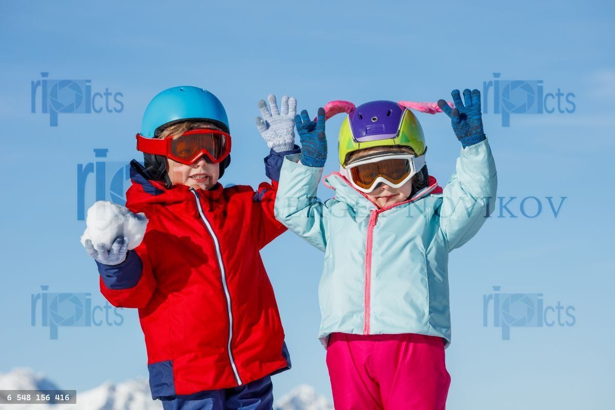 Happy boy and girl skiers enjoying a snowy day in the mountains