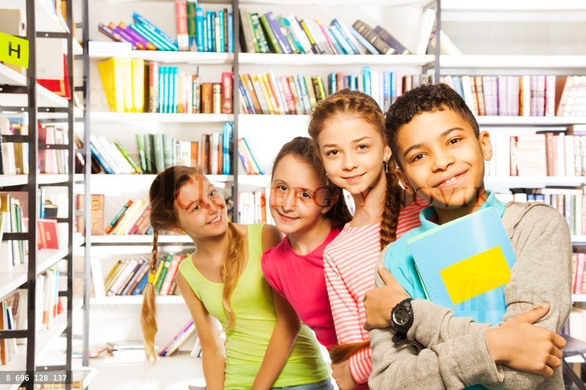 Four smiling kids standing in a row with books