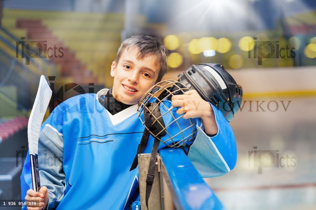 Young hockey player standing next to rink boards