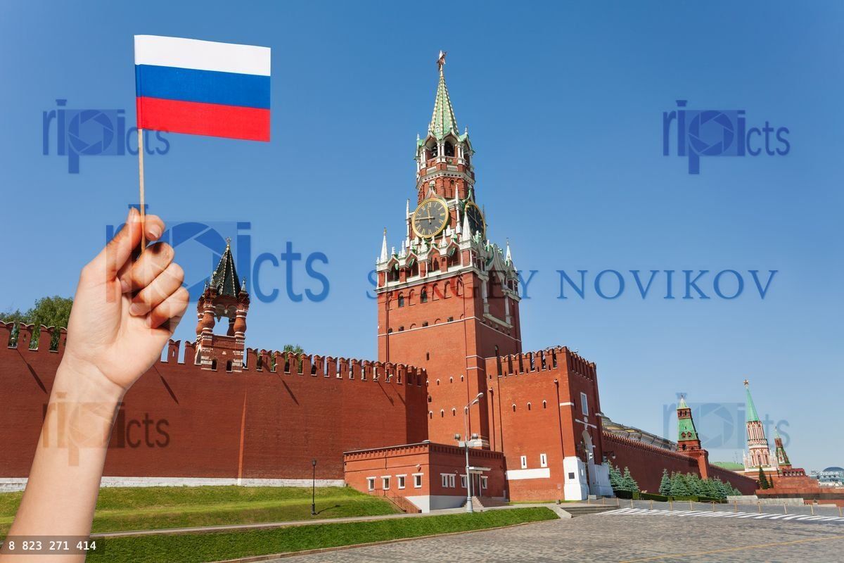 Woman's hand holding Russian flag against Kremlin