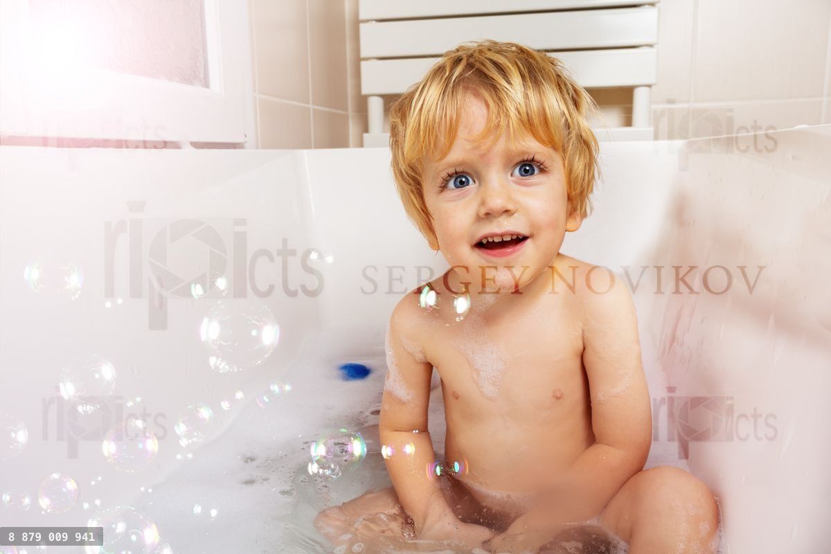Happy baby boy play with soap bubble in bathroom